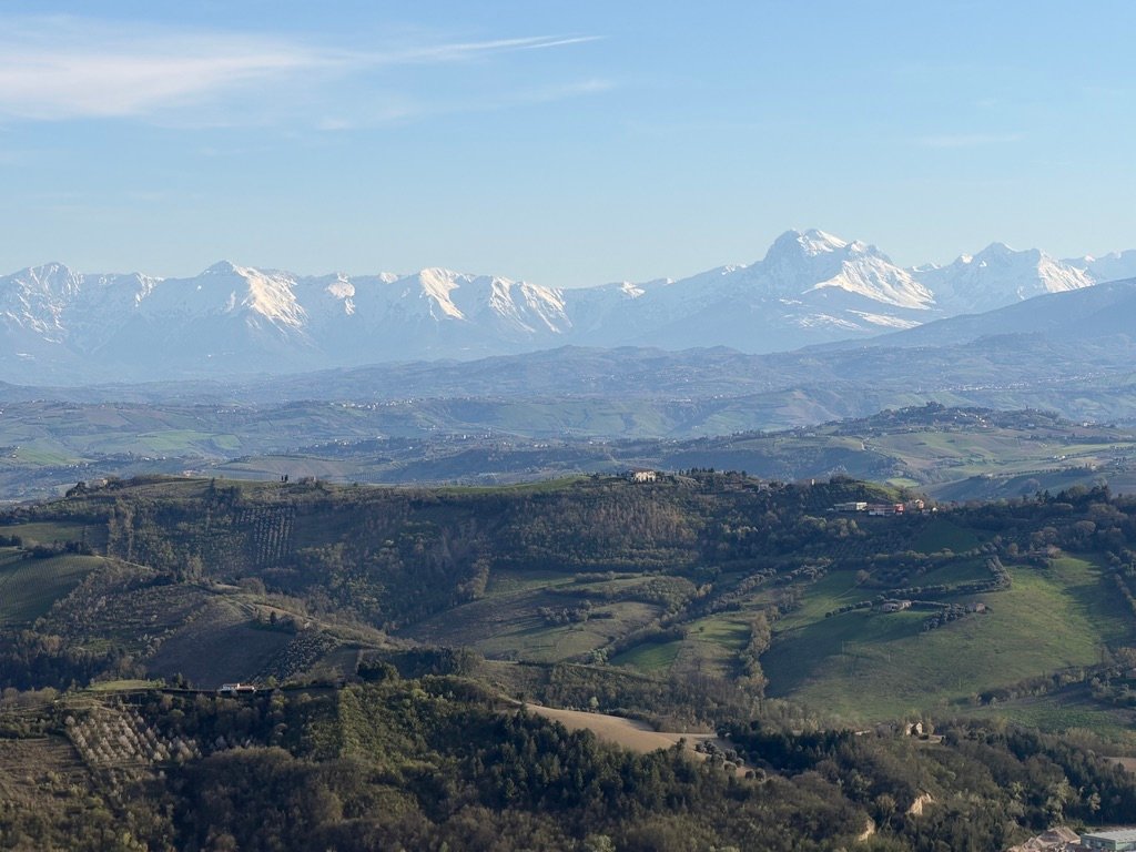 Uitzicht over de heuvels van Le Marche met de besneeuwde Sibillini bergen op de achtergrond